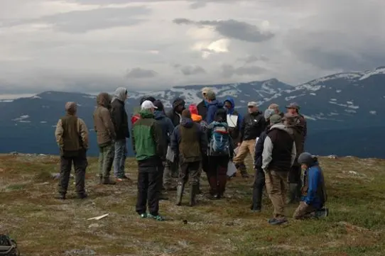 Personer står uppe på ett fjäll.