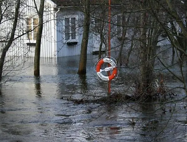 En livboj framför ett hus i ett översvämmat område.