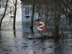 En livboj framför ett hus i ett översvämmat område.