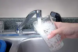 Person fyller på ett glas med vatten.