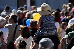 Ett barn sitter på en vuxens axlar i en folksamling