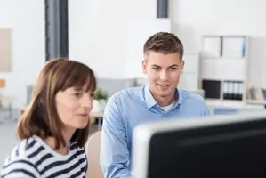 Två personer sitter vid en dator och samtalar