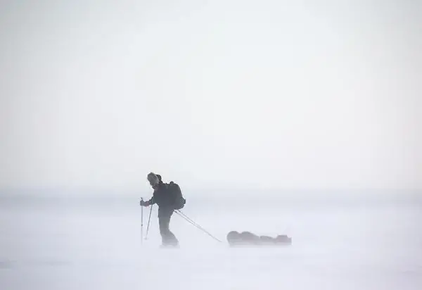 Person åker skidor genom ett snöigt landskap.