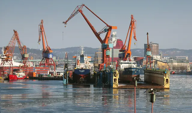 Bild som visar Göteborgs hamn, med fartyg och kranar i fokus och staden i bakgrunden. 