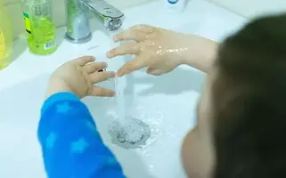 Barn tvättar händerna i ett handfat.