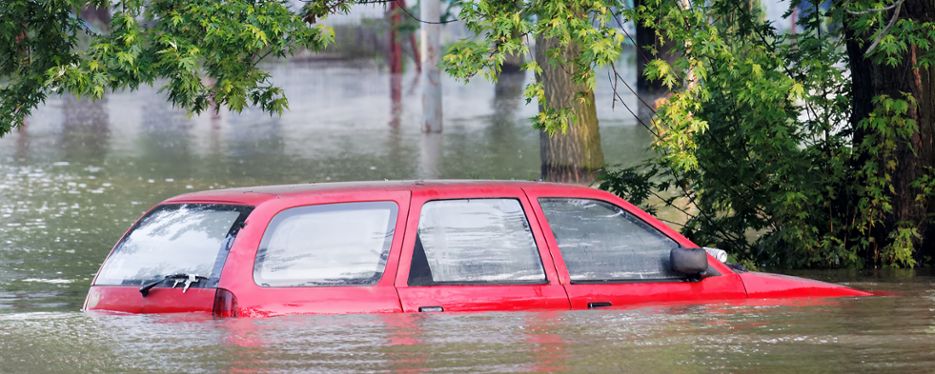 En översvämmad bil där vattnet når upp till fönstren.
