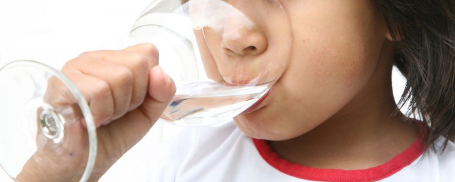 Ett barn dricker ett glas med vatten.