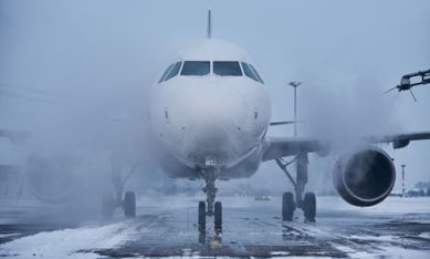 Flygplan på landningsbana med smält snö.